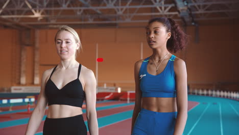 And-Female-Athletes-Talking-Together-While-Walking-On-An-Indoor-Track-After-A-Race