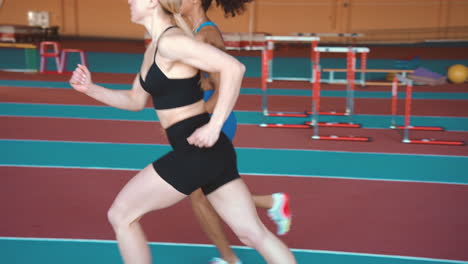 Seitenansicht-Von-Zwei-Multiethnischen-Sportlerinnen,-Die-Zusammen-Auf-Einer-Indoor-Bahn-Laufen-2