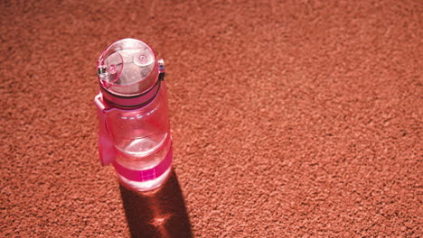 Close-Up-Shot-Of-A-Water-Bottle-On-A-Running-Track-In-An-Indoor-Sport-Facility