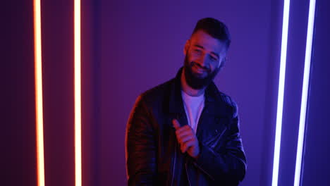 Close-Up-View-Of-Young-Man-Dancing-Looking-At-Camera-On-Purple-Neon-Lights-Background