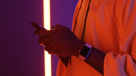 Amerikanische-Männliche-Hände-Mit-Smartwatch-Tippen-Und-Scrollen-Auf-Dem-Smartphone-Auf-Dem-Hintergrund-Der-Neonlampe