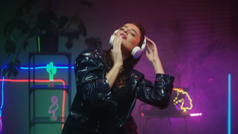 Brunette-Female-Dancer-In-Headphones-Dancing-While-Listening-To-Music-In-Futuristic-Room-Looking-At-Camera