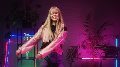 Happy-Teenage-Girl-With-Long-Blond-Hair-Dancing-Cheerfully-In-Room-With-Neon-Lights