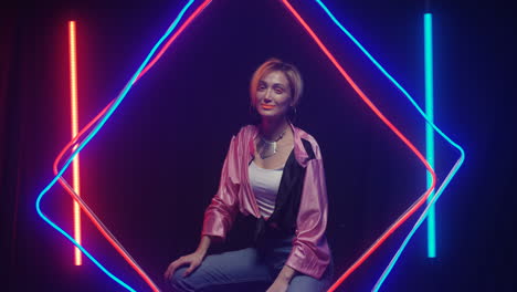 Young-Woman-With-Orange-Make-Up-And-Short-Hair-Looking-At-Camera-And-Smiling-In-Neon-Glowing-Tubes