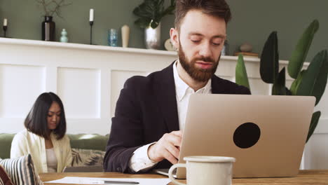 Businessman-Sitting-At-Table-And-Using-Laptop-Computer