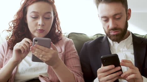 Woman-And-Man-In-Formal-Wear-Using-Mobile-Phone-And-Talking-Together-While-Sitting-On-Sofa-2