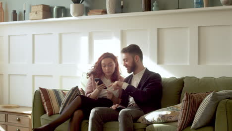 Woman-And-Man-In-Formal-Wear-Using-Mobile-Phone-And-Talking-Together-While-Sitting-On-Sofa-3