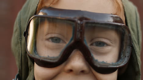 Nahaufnahme-Eines-Kleinen-Rothaarigen-Jungen-Mit-Fliegerbrille,-Der-In-Die-Kamera-Schaut-Und-Lächelt