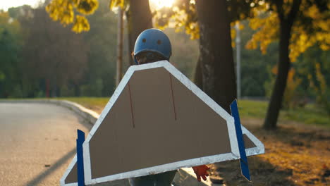 Back-View-Of-A-Little-Boy-In-Helmet-And-Red-Sweater-With-Cardboard-Airplane-Wings-Running-In-The-Park-On-A-Sunny-Day-And-Playing-As-A-Pilot