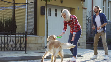 Young-Man-And-Woman-Playing-With-A-Labrador-Dog-On-The-Street-On-A-Sunny-Day-1