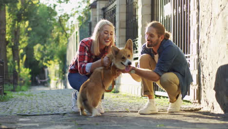 Young-Couple-Crouching-On-The-Street-And-Petting-Their-Corgi-Dog-On-A-Sunny-Day-2