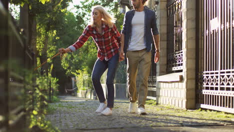 Young-Couple-Walking-Corgi-Dog-On-The-Leash-Along-The-Beautiful-Street