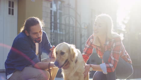 Happy-Young-Couple-Crouching-On-The-Street-And-Petting-Their-Labrador-Dog-On-A-Sunny-Day