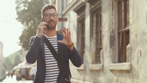 Handsome-Man-In-Stylish-Outfit-And-Glasses-Talking-On-The-Mobile-Phone-While-Walking-In-The-Old-Town