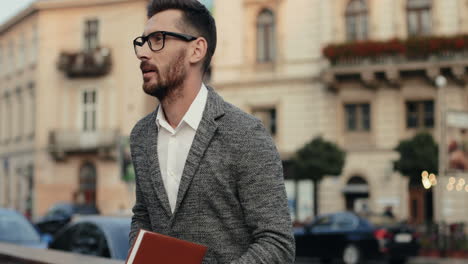 Stylish-Businessman-In-Glasses-Standing-In-The-Street,-Talking-On-The-Phone-And-Looking-At-His-Open-Planner,-Then-Going-Away