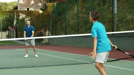 Rückansicht-Eines-Teenagers,-Der-Mit-Seinem-Vater-Tennis-Spielt-Und-Das-Spiel-Verliert