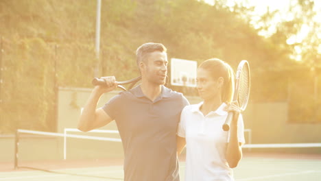 Happy-Couple-Hugging-And-Leaving-Tennis-Court-In-Sunlight-Of-Sunset