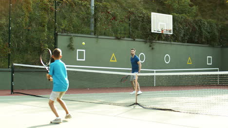 Rückansicht-Eines-Teenagers,-Der-Mit-Seinem-Vater-Tennis-Spielt-Und-Das-Match-Gewinnt