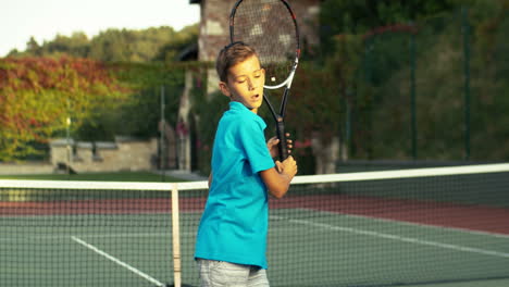 Teen-Boy-With-Racket-Training-On-Outdoor-Tennis-Court-On-A-Summer-Day