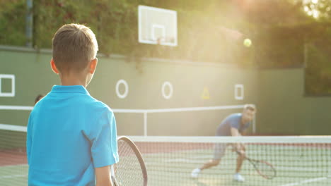 Rückansicht-Eines-Teenagers,-Der-Im-Sommer-Mit-Vater-Und-Kleiner-Schwester-Auf-Einem-Außenplatz-Tennis-Spielt-1