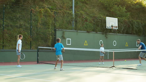 Glückliche-Familie,-Die-Im-Sommer-Auf-Einem-Außenplatz-Tennis-Spielt-3
