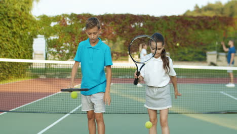 Sister-And-Brother-Playing-At-Tennis-Court-And-Hitting-Balls-Against-The-Ground-With-Racket-1