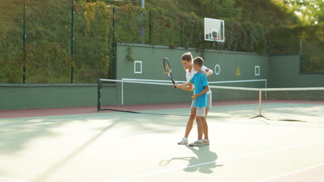 Frau,-Die-Seinem-Jugendlichen-Sohn-Beibringt,-Wie-Man-An-Einem-Sommertag-Tennis-Spielt