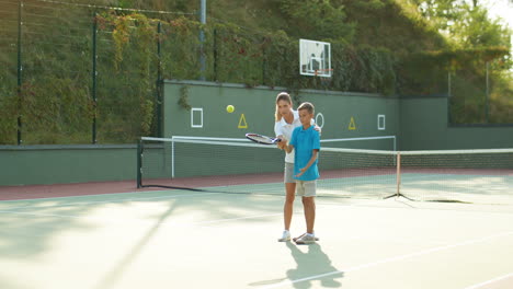 Woman-Teaching-His-Teen-Son-How-To-Play-Tennis-On-A-Summer-Day-2