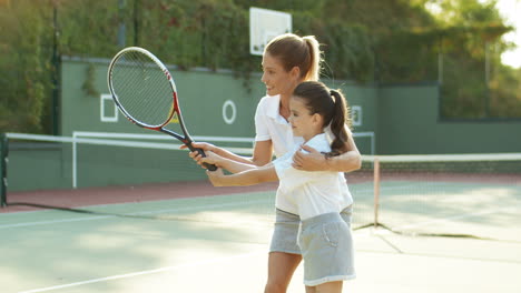 Loving-Woman-Teaching-Her-Cute-Little-Daughter-How-To-Play-Tennis-At-Sport-Court-On-A-Summer-Day-3