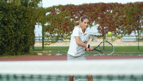 Blonde-Woman-Playing-Tennis-And-Hitting-Ball-With-Racket-On-Sunny-Summer-Day-At-Sport-Court