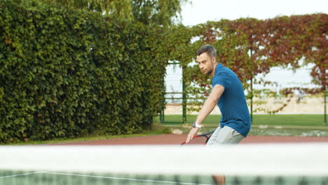 Handsome-Man-Playing-Tennis-And-Hitting-Ball-With-Racket-On-A-Summer-Day-At-Sport-Court