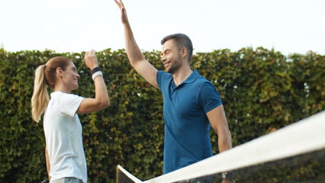 Happy-Couple-Giving-High-Five-Over-The-Net-After-Playing-Tennis-Together