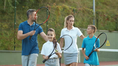 Glückliche-Familie,-Die-Gemeinsam-Den-Platz-Verlässt,-Nachdem-Sie-An-Einem-Sommertag-Tennis-Gespielt-Hat