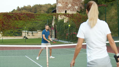 Glückliches-Paar,-Das-Zusammen-Tennis-Spielt-Und-Dann-An-Einem-Sommertag-Auf-Dem-Außenplatz-High-Five-Gibt