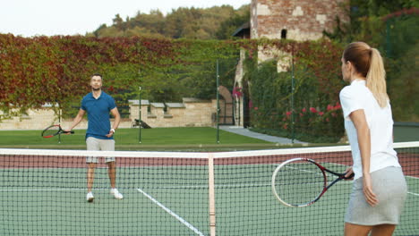 Rear-View-Of-Sporty-Woman-Playing-Tennis-With-Man-At-Outdoor-Court-On-A-Summer-Day-1