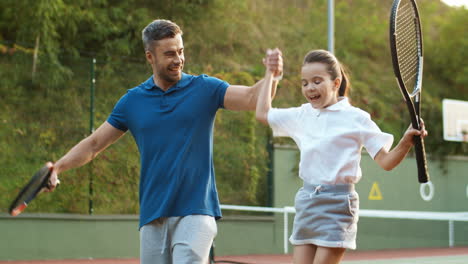 Loving-Dad-And-Happy-Little-Daughter-Holding-Hands-And-Leaving-Tennis-Court-Together