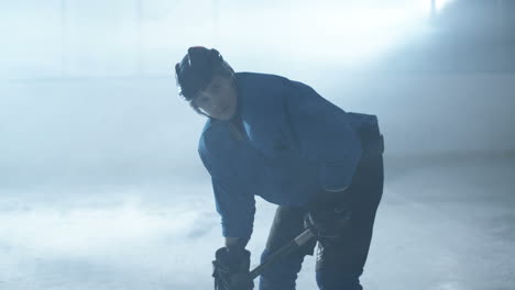 Portrait-Shot-Of-A-Concentrated-Male-Hockey-Player-Holding-Stick-And-Looking-At-Camera-On-The-Ice-Arena