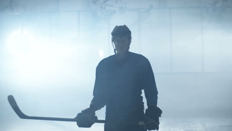 Portrait-Shot-Of-A-Concentrated-Male-Hockey-Player-Standing-On-The-Ice-Arena,-Holding-Stick-And-Looking-At-Camera