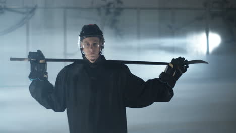Portrait-Shot-Of-A-Young-Male-Hockey-Player-Holding-Club-Over-Shoulders-And-Looking-At-The-Camera-On-The-Ice-Arena