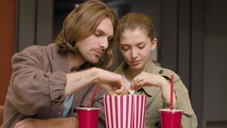 Glückliches-Paar,-Das-Popcorn-Isst,-Während-Es-An-Der-Kino-Snackbar-Redet-Und-Lacht