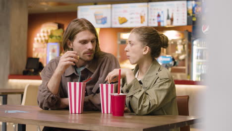 Loving-Couple-Eating-Popcorn-And-Talking-Together-At-The-Cinema-Snack-Bar-1