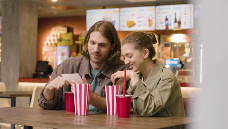Couple-Talking-Together-While-Eating-And-Drinking-At-The-Cinema-Snack-Bar