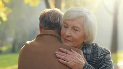 Rear-View-Of-Elderly-Man-Hugging-Her-Partner-At-Sunset-In-The-Park-In-Autumn