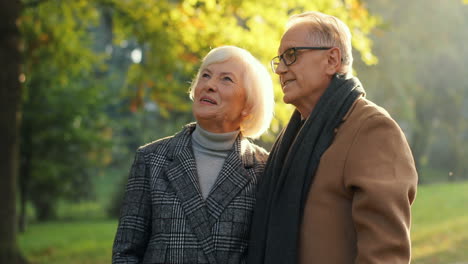 Elderly-Couple-Standing-At-Sunset-In-The-Park-During-A-Walk