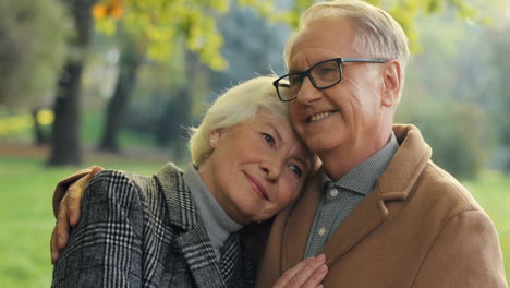 Elderly-Married-Couple-Hugging-In-The-Autumn-Park