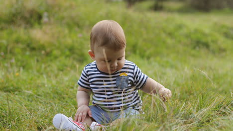 Retrato-De-Un-Adorable-Bebé-Sentado-En-La-Hierba-Verde-Y-Sonriendo-En-El-Parque