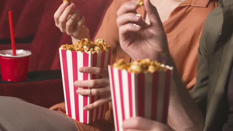Close-Up-View-Of-Couple-Hands-Holding-Popcorn-In-The-Cinema