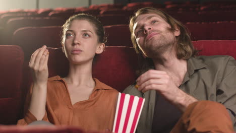 Glückliches-Paar-Sitzt-Im-Kino,-Während-Sie-Reden-Und-Popcorn-Essen-Und-Darauf-Warten,-Den-Film-Zu-Sehen-1