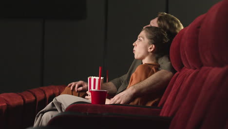 Couple-Hugging-Sitting-In-The-Cinema-While-They-Watching-A-Movie-And-Eating-Popcorn