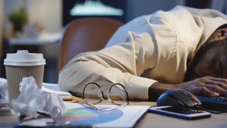 Close-Up-View-Of-Man-Office-Worker-Sleeping-On-The-Desk-Full-Of-Empty-Coffee-Cups-In-The-Night